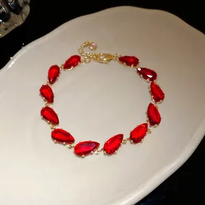 Detailed macro view of teardrop-shaped red zircon stones on a gold-plated luxury bracelet