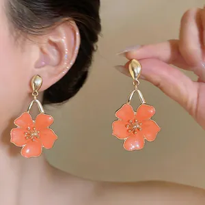 Detailed macro view of elegant peach enamel flower drop earrings with gold finish