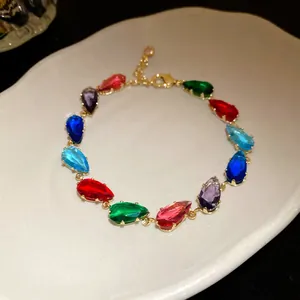 Detail of teardrop-shaped colorful zircon stones on gold-plated link bracelet