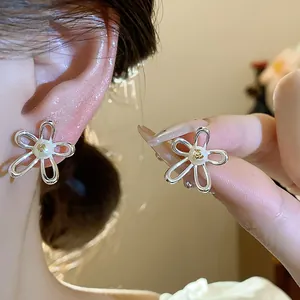 Macro detail of elegant silver hollow flower stud earrings with a central pearl