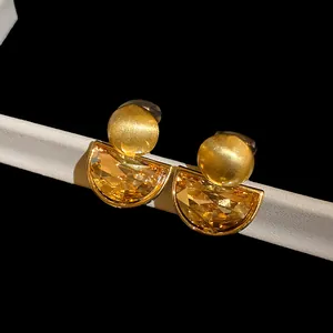 Close-up of retro semi-circular amber crystal drop clip-on earrings with matte gold.