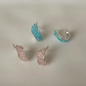 Primo piano di orecchini a lobo in argento intrecciato con cristalli blu e rosa scintillanti