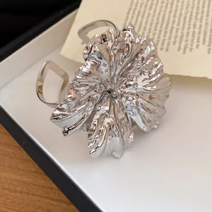 Close-up of the intricate silver metallic flower texture on an open cuff bracelet.