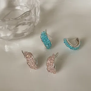 Dettaglio di eleganti orecchini a perno intrecciati con cristalli rosa e blu