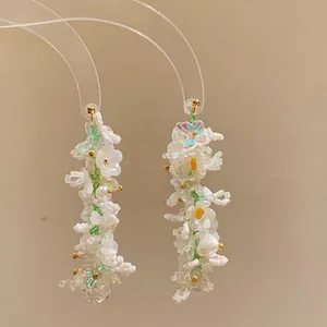 Detail of handmade beaded earrings with white flowers and pearls