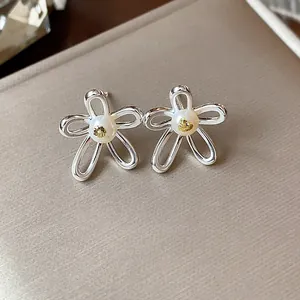 Close-up of elegant hollow flower stud earrings with pearl centers and gold accents
