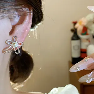 Detailed close-up showing a minimalist silver hollow flower stud earring with a pearl on ear