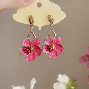 Close-up of sweet pink enamel flower dangle earrings on a ginkgo leaf card.