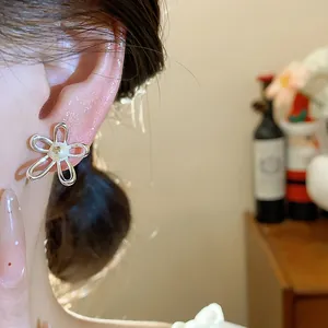 Detailed close-up of minimalist silver hollow flower stud earrings with elegant pearl center