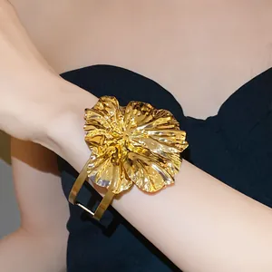 Detailed macro view of the gold metallic wrinkled flower on a double-layer cuff