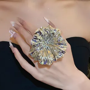 Detailed view of a large oversized gold metallic ruffled flower statement ring on a hand