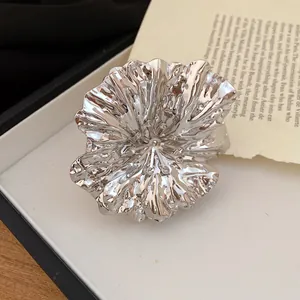 Detailed macro view of a silver pleated flower bangle on a vintage paper background