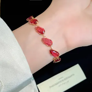 Close-up of elegant gold-plated bracelet featuring vibrant red teardrop zircons.