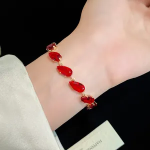 Close-up of luxury gold bracelet with vibrant red teardrop-shaped cubic zirconia.