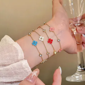 Primer plano de delicadas pulseras de acero inoxidable con flores de esmalte y circonitas.