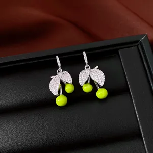 Detail view of silver earrings with leaf design, zircon stones and vibrant green beads.