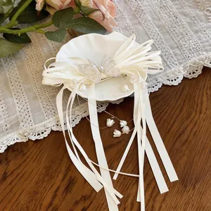 Détail élégant d'une barrette papillon avec longs rubans blancs et pendentifs muguet
