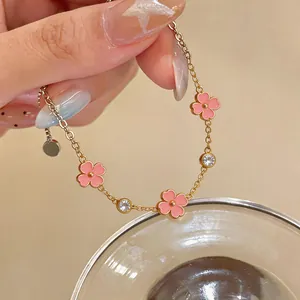 Detalle de una delicada pulsera de acero inoxidable con flores de esmalte rosa y circonitas