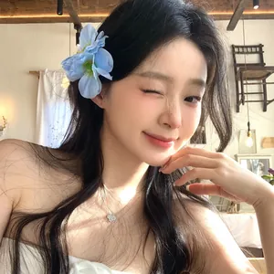 Close-up of a blue fabric flower hair clip worn by a model in a cozy cafe setting