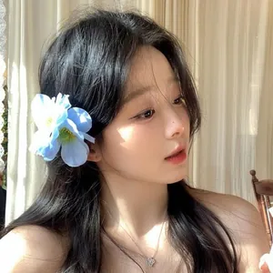 Elegant blue fabric flower hair clip accessory worn by a beautiful Asian model in sunlight