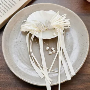 Détail des rubans de soie crème et des pendentifs muguet sur une pince à cheveux papillon