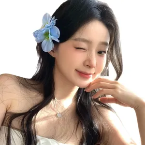 Sweet blue fabric flower hair clip worn by a model for a stylish vacation look
