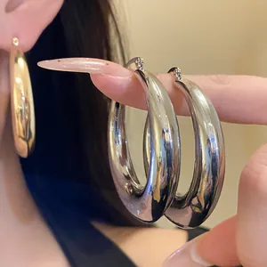 Detailed macro view of oversized chunky polished metal hoop earrings in silver and gold finishes.