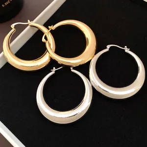 Close-up detail of luxury polished gold and silver thick hollow metallic hoop earrings