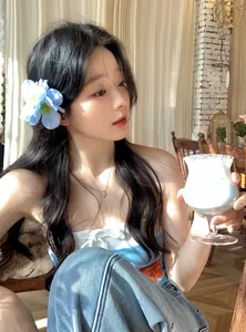 Elegant blue fabric flower hair clip worn by a model in a sunlit cafe setting.