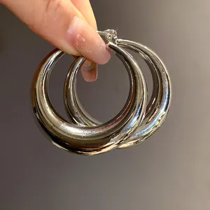 Detailed macro shot of thick shiny silver metallic hoop earrings with a mirror-like finish