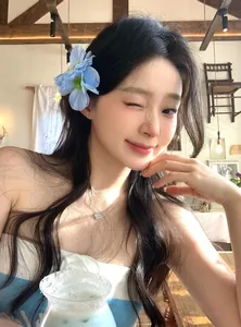 Exquisite blue fabric flower hair clip worn by an Asian model in a bright cafe setting