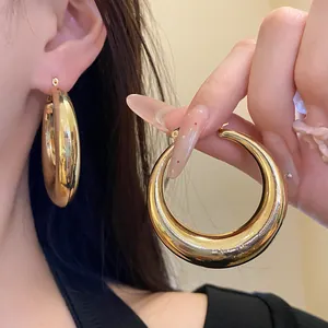 Detail shot of chunky gold hoop earrings with a high-polish glossy finish for women.