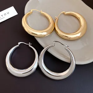 Close-up detail of high-shine chunky metal hoop earrings in gold and silver finishes.