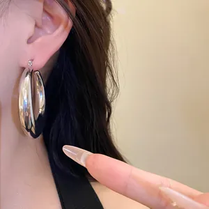 Close-up of a chunky silver metallic hoop earring worn on model's ear