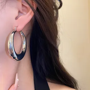 Close-up of a silver chunky hoop earring worn on an ear with a sleek metallic finish