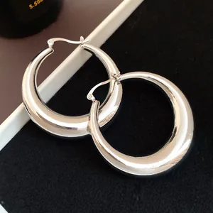 Detailed close-up of shiny silver metallic chunky hoop earrings with a hollow design