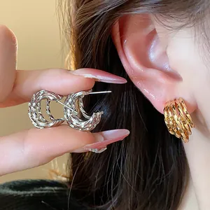 Close-up view of 18k gold plated C-shaped hoop earrings with a stylish textured finish
