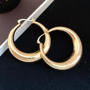 Macro detail view of thick gold-finished metallic glossy chunky hollow hoop earrings