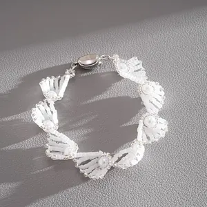 Nahaufnahme der Textur eines eleganten weißen Glasperlen- und Imitationsperlenarmbands