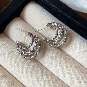 Detailed macro view of silver-toned multi-layered twisted texture C-shaped hoop earrings
