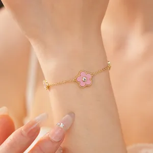 Nahaufnahme eines vergoldeten Armbands mit rosa Blumenanhängern und einem funkelnden Zirkon