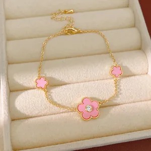 Detailansicht eines vergoldeten Armbands mit rosa Blumen und Zirkon-Mitte