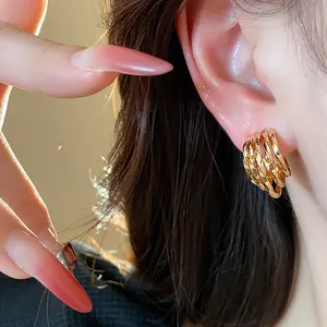 Close-up detail of 18k gold plated C-shaped layered hoop earrings worn by a model