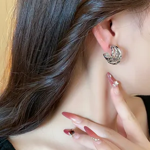 Detail shot of silver-plated C-shaped earrings with a stylish twisted layered design