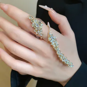 Detailed view of a sparkling zircon leaf open ring on a hand with elegant long manicure
