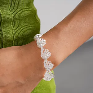 Detailansicht eines weißen wellenförmigen Glasperlenarmbands mit eleganten Perlen am Handgelenk.