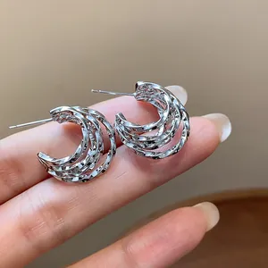Detail view of silver-plated C-shaped hoop earrings with multi-layered twisted design.