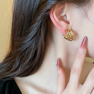 Close-up of elegant 18k gold plated twisted C-shape hoop earrings on a female model