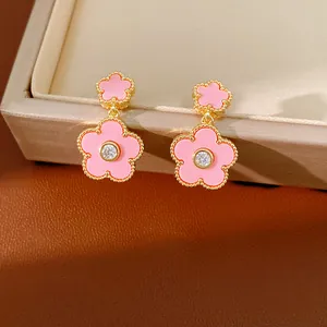 Detailaufnahme der vergoldeten rosa Blumenohrringe mit einem funkelnden Zirkonstein.