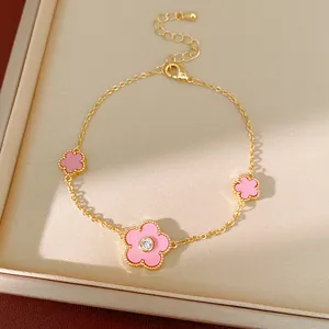 Detailansicht eines vergoldeten Armbands mit rosa Blumen und einem Zirkonia-Stein.